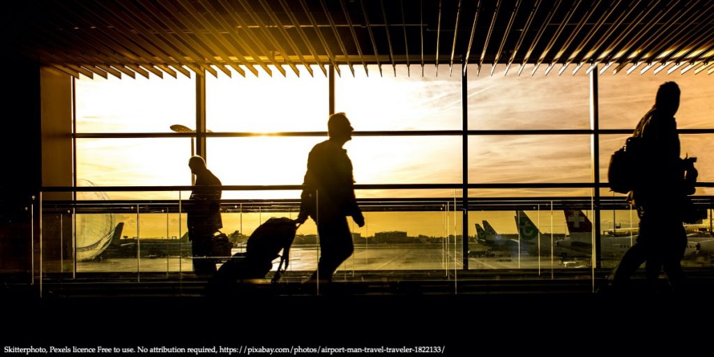 Image of a man walking inside the airport with his luggage representing a mobility of Scientists