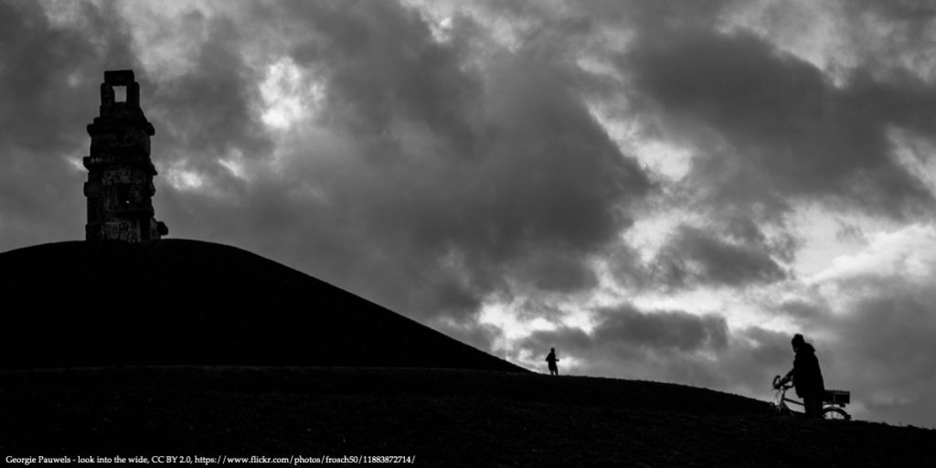 Dark hill on the right side of the image with a shadow of a man holding his bicycle on the right side