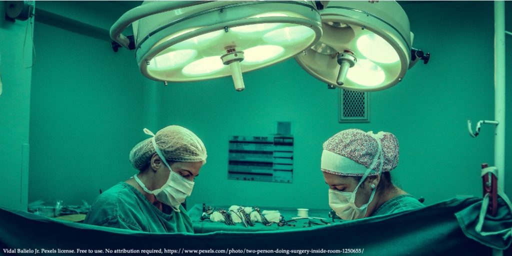 An image of surgery room with two doctors in green protection gear representing public healthcare expenditures