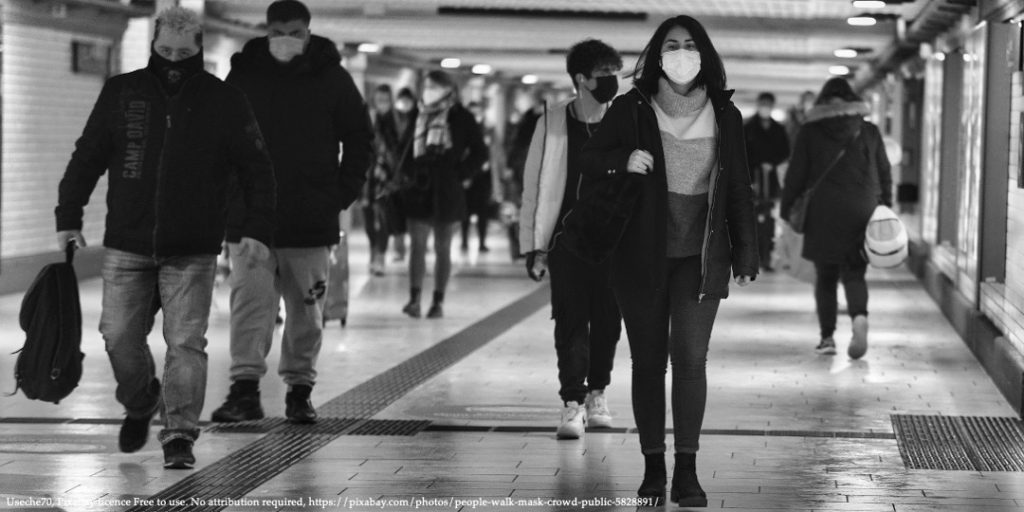 A black and white colour image with people walking through the tunnel wearing masks and representing COVID-19 in Eastern Europe