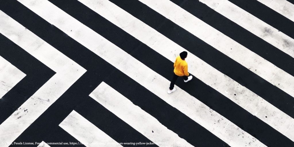 Image with black and white stripes and person in yellow jacket walking representing conference on rethinking gender