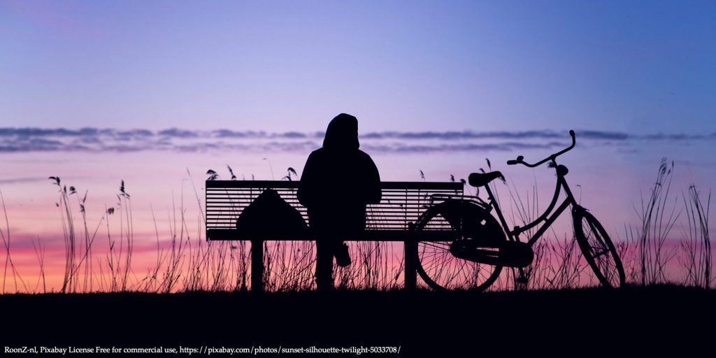 Image of a woman sitting alone in the sunset representing dimensions of well-being