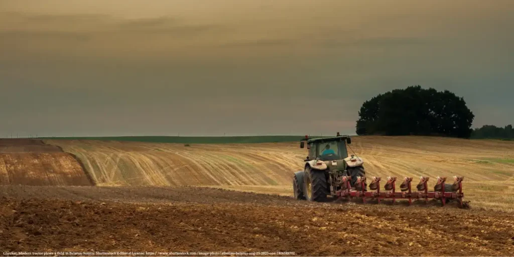 A tractor plowing a field in Belarus during the early autumn harvest, illustrating the country's agricultural sector representing report that discuss Belarus GDP slowdown.