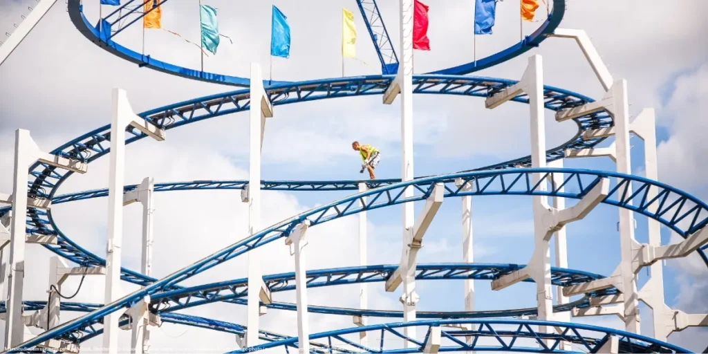 A person performing high-altitude cleaning on a roller coaster structure, symbolizing bravery and entrepreneurship spirit in Belarus, with future generations and children in mind.