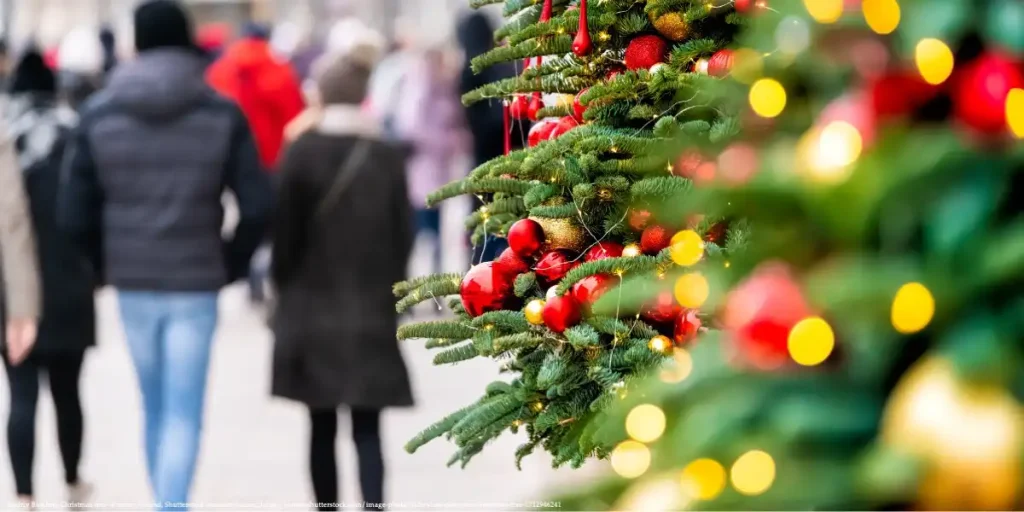 Christmas tree with festive red and gold decorations on a street during Christmas time in Poland, with people in winter clothes walking in the background.